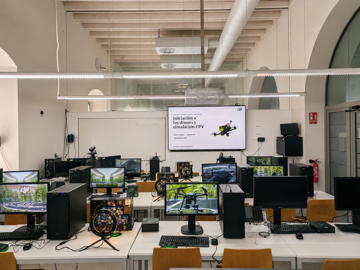 El aula preparada antes de empezar: filas de ordenadores con el simulador cargado y la presentación en pantalla