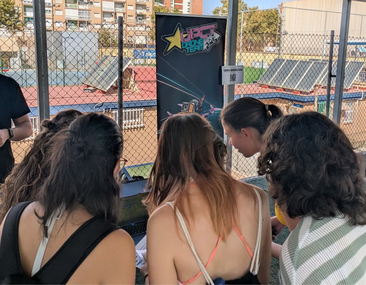 Varias estudiantes se turnan ante el portátil para probar el simulador de vuelo, con el roll-up del equipo detrás