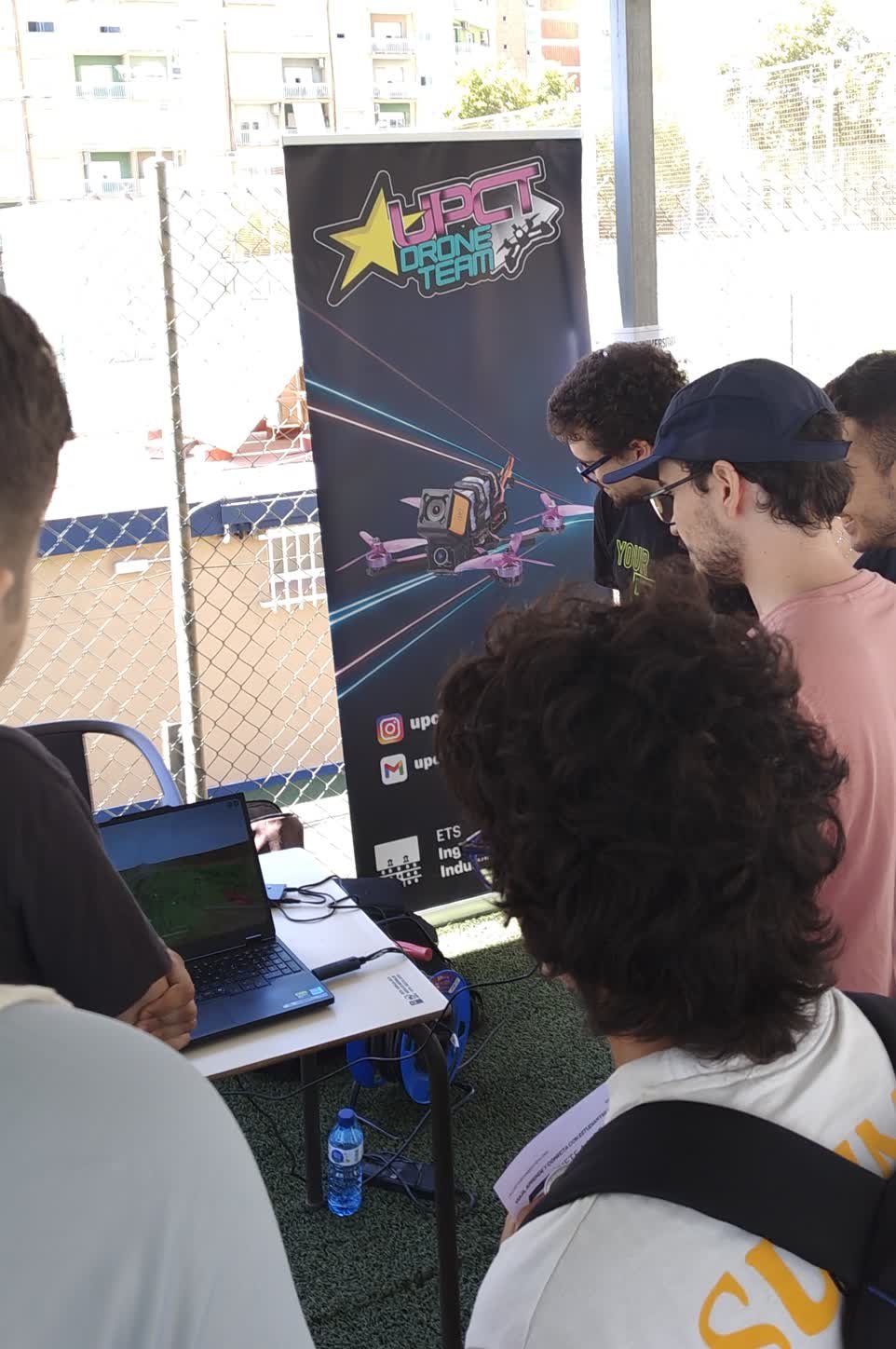 Un grupo de estudiantes alrededor del portátil mientras uno de ellos pilota en el simulador