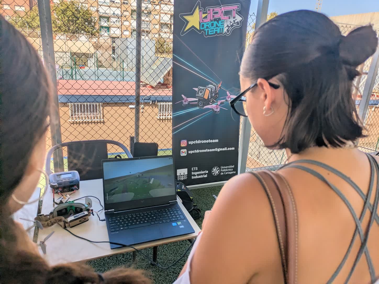 El puesto del equipo en la jornada: el portátil con el simulador en marcha, la emisora, las gafas FPV y un dron sobre la mesa