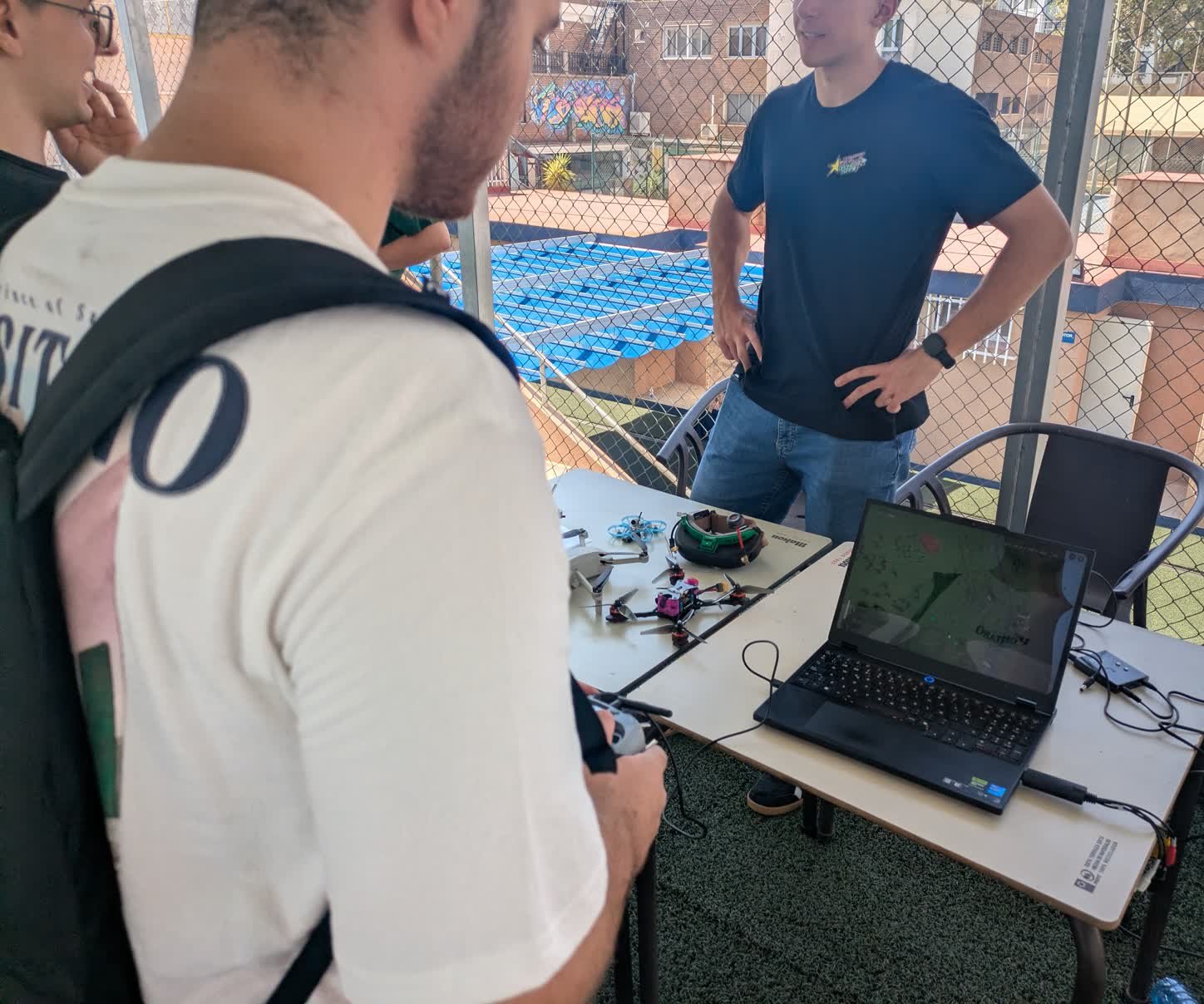 Un visitante pilota en el simulador con la emisora mientras un miembro del equipo le explica desde el otro lado de la mesa